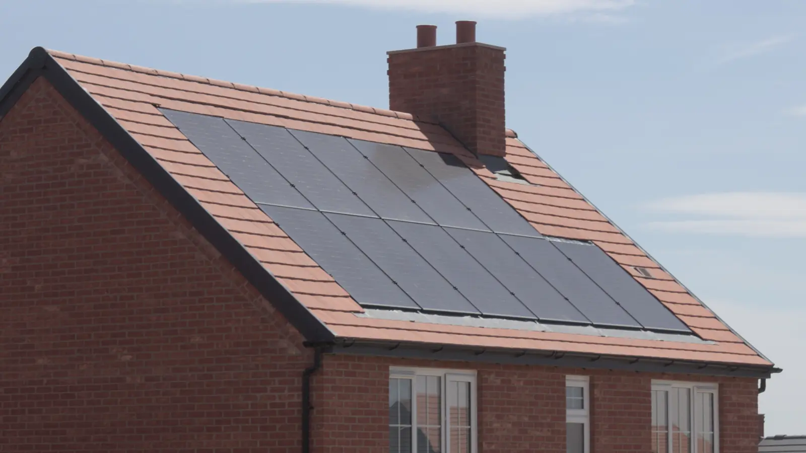 Solar panels covering the main roof plane of a brick house